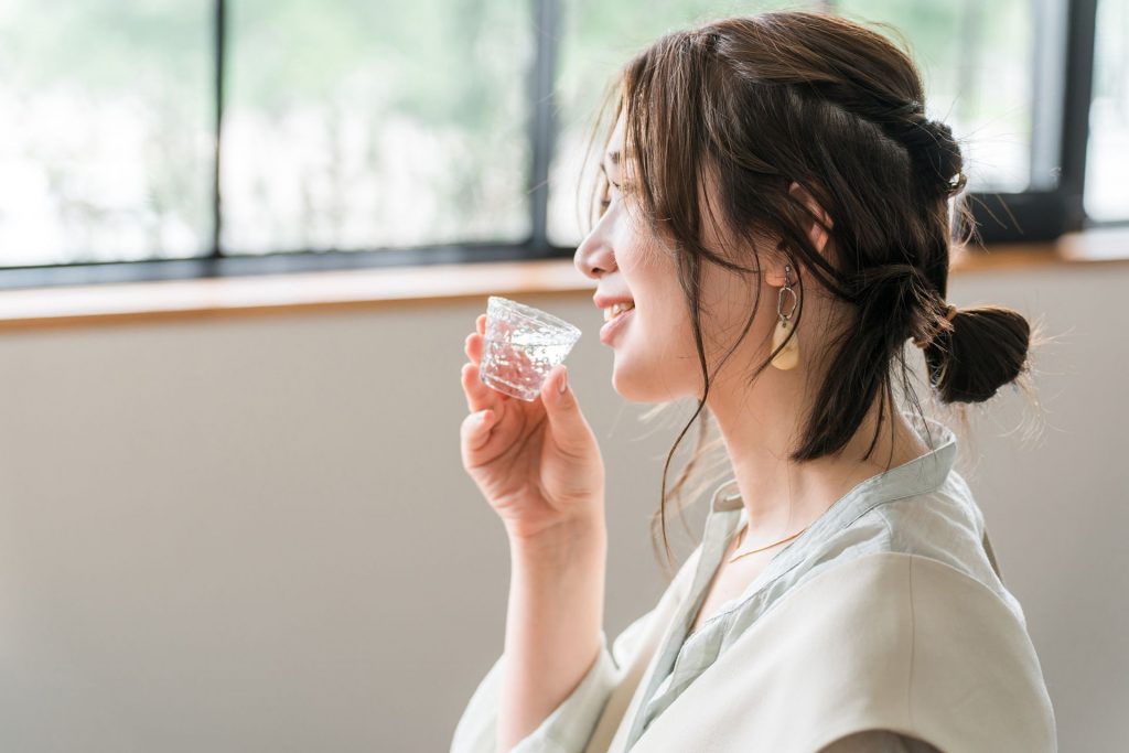 窓辺で日本酒を飲む女性